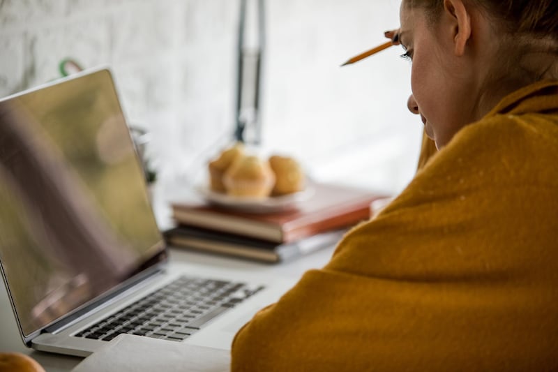 Cut out, side view of female worker attending a virtual meeting with her laptop computer while spending isolation days at home. Getty Images