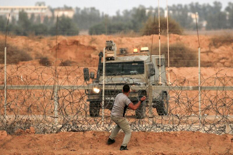 A Palestinian protester hurles stones at a vehicle during clashes with Israeli forces following a demonstration along the border with Israel east of Khan Yunis in the southern Gaza strip on October 25, 2019. / AFP / SAID KHATIB
