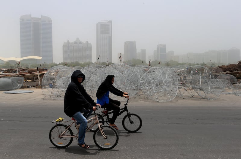 ABU DHABI - UNITED ARAB EMIRATES - 07JUNE2015 - Hazy and dusty weather keeps these two cyclist cover they head yesterday at the fishing harbour in Abu Dhabi. Ravindranath K / The National (Standalone for News) *** Local Caption ***  RK0706-WEATHER04.jpg