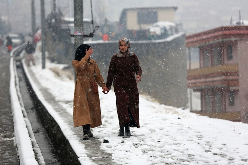 Women make their way along a snow-covered street in Kabul. AFP