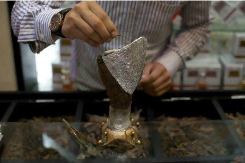 A shop worker drops a piece of oud into a burner at Ibn Battuta Mall.