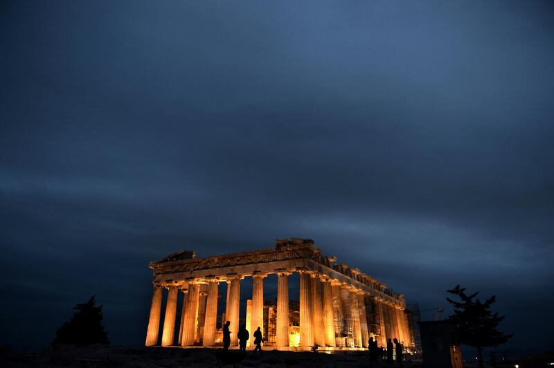 People stand in front of the ancient Temple of Parthenon atop the Acropolis hill on October 4, 2013. AFP PHOTO / ARIS MESSINIS / AFP PHOTO / ARIS MESSINIS
