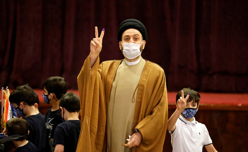 Ammar al-Hakim, Leader of the Hikma movement and accompanied by his children, shows his inked finger at a polling station in Baghdad, as Iraqis go to the polls to vote in the parliamentary election, in Iraq, October 10, 2021. REUTERS/Thaier al-Sudani