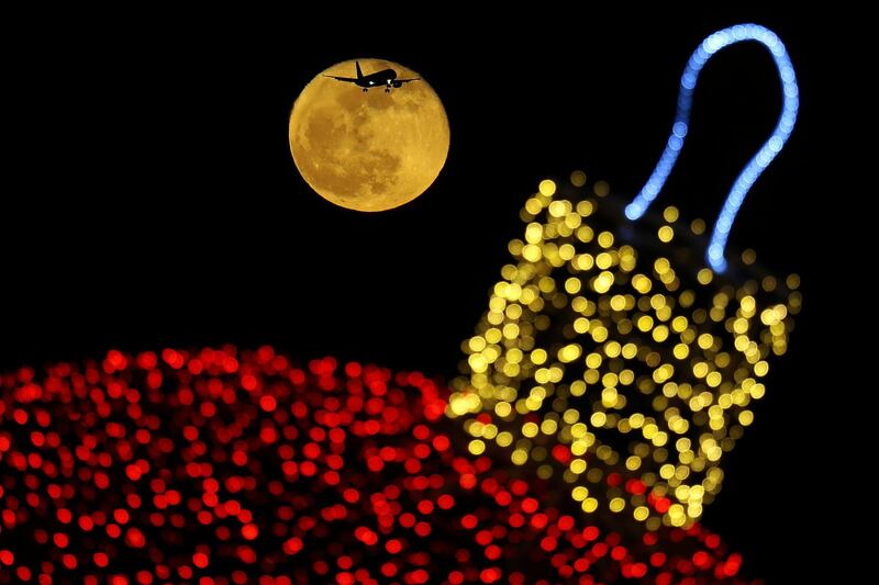 The moon shines behind a Christmas ornament as an aircraft prepares for landing at the airport in Larnaca, Cyprus. AP