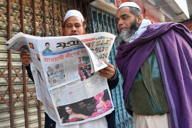 Bangladeshi people read a newspaper carrying headlines of the general election results in Dhaka on December 31, 2018. Bangladesh Prime Minister Sheikh Hasina has secured a fourth term with a landslide victory in polls the opposition slammed as "farcical" over claims of vote-rigging, and clashes between rival supporters that killed at least 17 people.
 / AFP / Indranil MUKHERJEE
