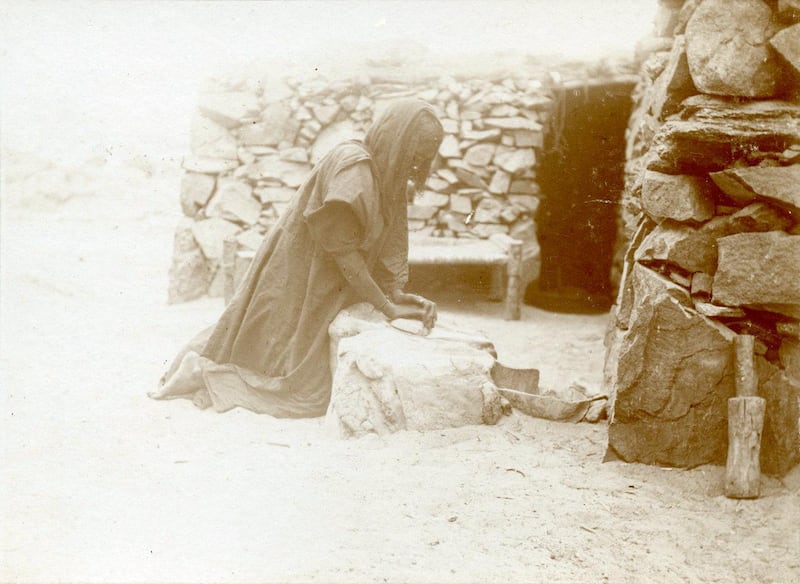 A Nubian woman is seen grinding grain.