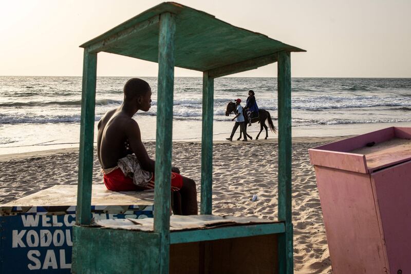 A woman takes a horse ride along a beach in Banjul, Gambia. AFP