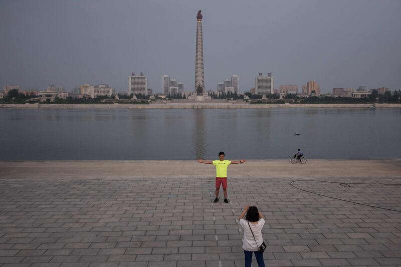 A tourist poses for a photo before the Taedong river in Pyongyang. AFP