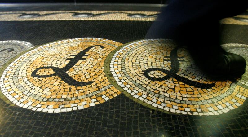 FILE PHOTO: An employee is seen walking over a mosaic of pound sterling symbols set in the floor of the front hall of the Bank of England in London, March 25, 2008.   REUTERS/Luke MacGregor/File Photo