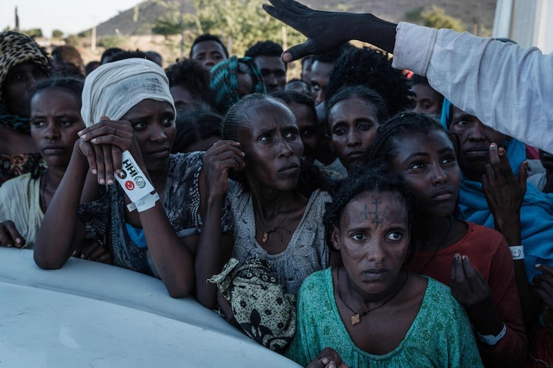 TOPSHOT - Ehiopians, who fled the Ethiopia's Tigray conflict as refugees, wait for food distribution in front of a warehouse at Um Raquba refugee camp in Gedaref, eastern Sudan, on December 1, 2020.  More than 45,000 people have escaped from northern Ethiopia since November 4, after Prime Minister Abiy Ahmed ordered military operations against leaders of Tigray's ruling party in response to its alleged attacks on federal army camps. / AFP / Yasuyoshi CHIBA
