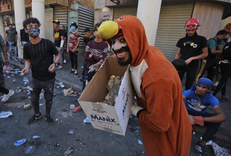 A constumed Iraqi protester carries a box of rocks to be hurled at security forces during clashes with them in the capital Baghdad. AFP