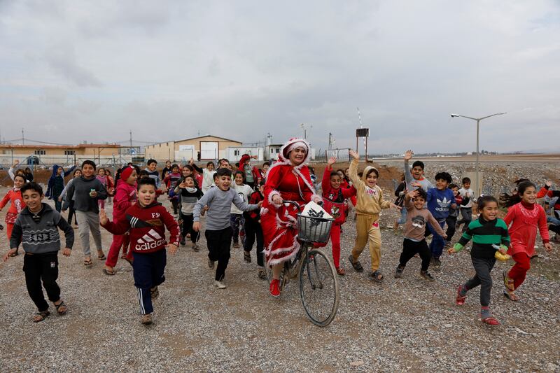 A woman dressed as Santa Claus rides her bicycle at Baharka camp for displaced people in Erbil, Iraq. Reuters