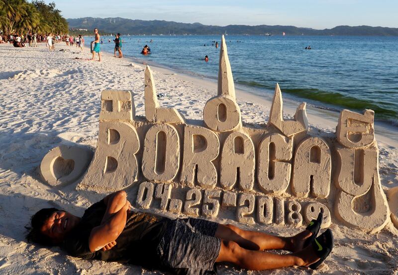 A tourist poses in front of a sand sculpture, a day before the temporary closure of the holiday island Boracay. Erik De Castro / Reuters