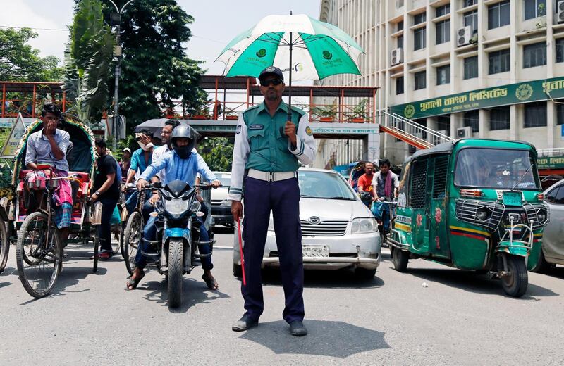 A Bangladeshi traffic policeman on duty has an umbrella in his hand against the sunshine as he directs traffic in the Shahbag area of Dhaka, Bangladesh.  EPA / MONIRUL ALAM