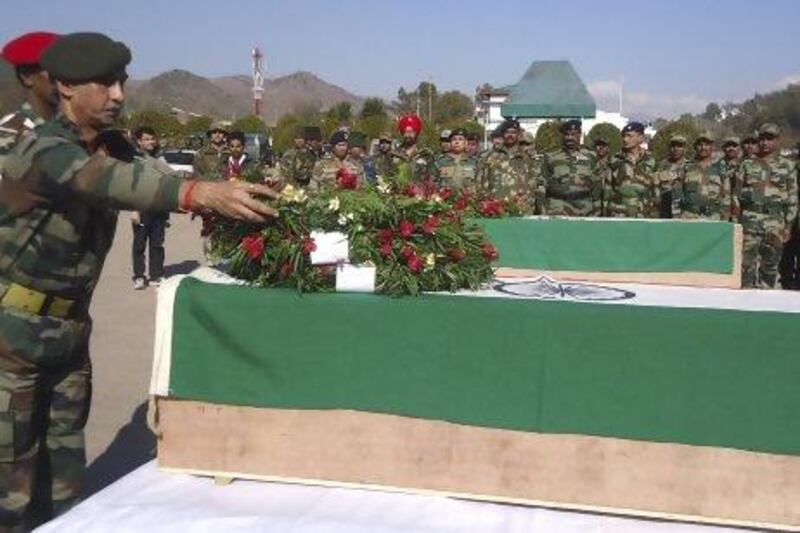 An Indian soldier places a wreath on a coffin containing the body of a colleague after two soldiers died in a rare firefight in disputed territory.