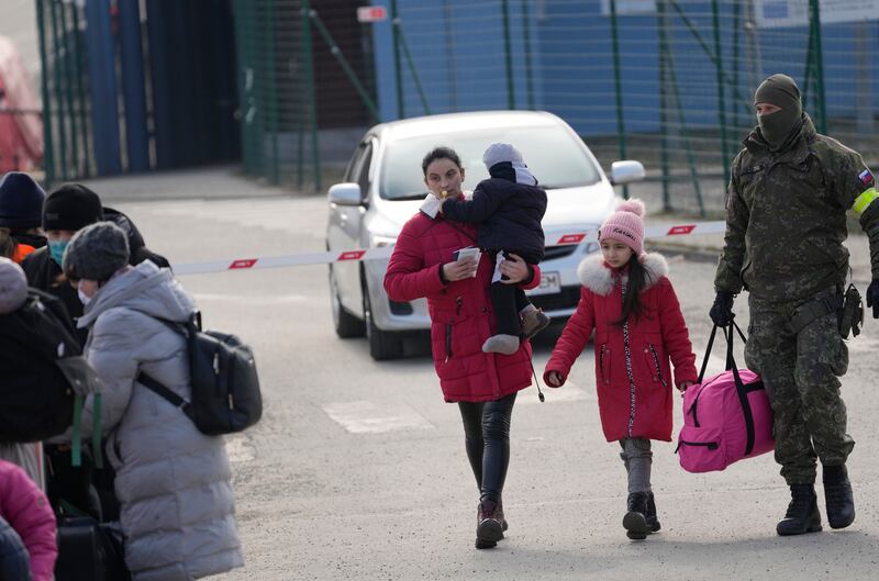 A woman fleeing Ukraine carries a child as she crosses the border in Vysne Nemecke, Slovakia. AP
