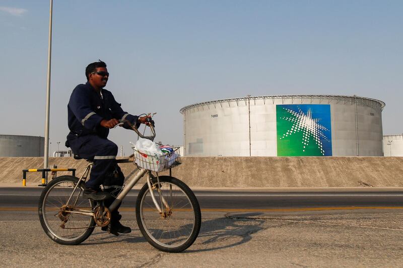 An employee rides a bicycle next to oil tanks at Saudi Aramco oil facility in Abqaiq, Saudi Arabia. Reuters