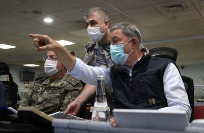 Turkish Defense Minister Hulusi Akar, right, and army commanders wearing face masks to protect against the coronavirus, speak at a military headquarter, in Ankara, Turkey, Monday, June 15, 2020. Turkey's jets have carried out new cross-border air strikes against outlawed Kurdish rebel targets in northern Iraq, the Turkish Defense Ministry said Monday. (Turkish Defense Ministry via AP, Pool)