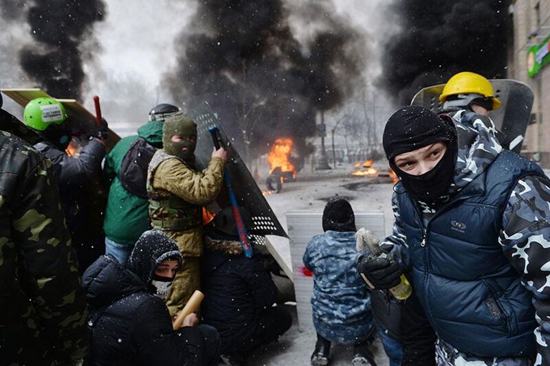A demonstrator holds an incendiary device as protesters clash with police in the center of Kiev on January 22, 2014. At least two activists were shot dead today as Ukrainian police stormed protesters' barricades in Kiev, the first fatalities in two months of anti-government protests. Pitched battles raged in the centre of the Ukrainian capital as protesters hurled stones at police and the security forces responded with tear gas and rubber bullets. AFP PHOTO / SERGEI SUPINSKY
