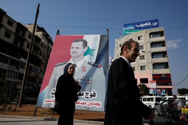People walk in front of a billboard with a picture of Syrian President Bashar Al Assad in Homs. Reuters