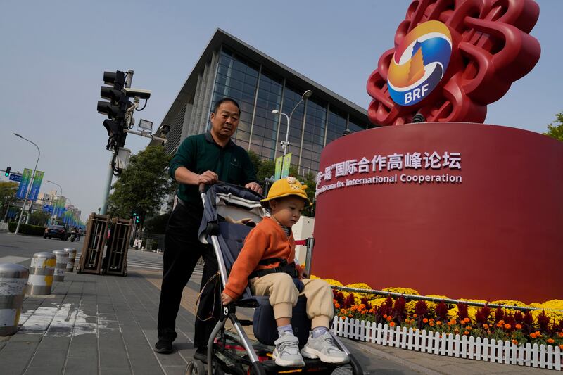 Residents pass by the logo for the Belt and Road Forum outside the China National Convention Centre in Beijing. AP