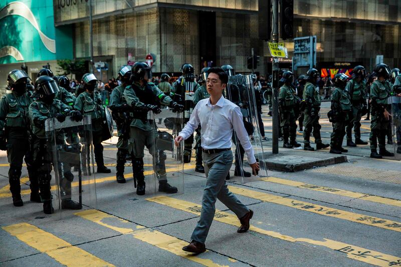 A pedestrian walks past a police line after office workers and pro-democracy protesters held a demonstration in Central in Hong Kong on November 15, 2019.  Thousands of pro-democracy protesters took to Hong Kong's streets, defying a warning by Chinese President Xi Jinping, as a campaign of mass disruption extended into a fifth straight day. / AFP / ISAAC LAWRENCE
