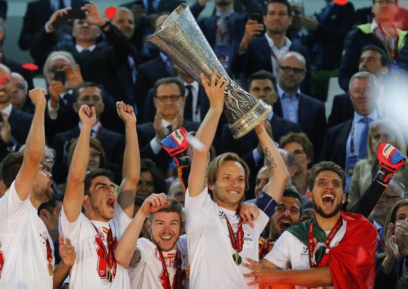 Sevilla captain Ivan Rakitic lifts the Europa League trophy as his teammates celebrate after defeating Benfica in Turin, Italy, on May 14, 2014. Sevilla won 4-2 on penalties. Armando Babani / EPA
