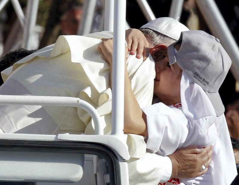Pope Francis hugs a boy before celebrating a mass at the Amman stadium in the Jordanian capital on May 24, 2014. Pope Francis made an urgent plea today for peace in war-torn Syria as he kicked off a three-day pilgrimage to the Middle East. AFP PHOTO / KHALIL MAZRAAWI (Photo by KHALIL MAZRAAWI / AFP)