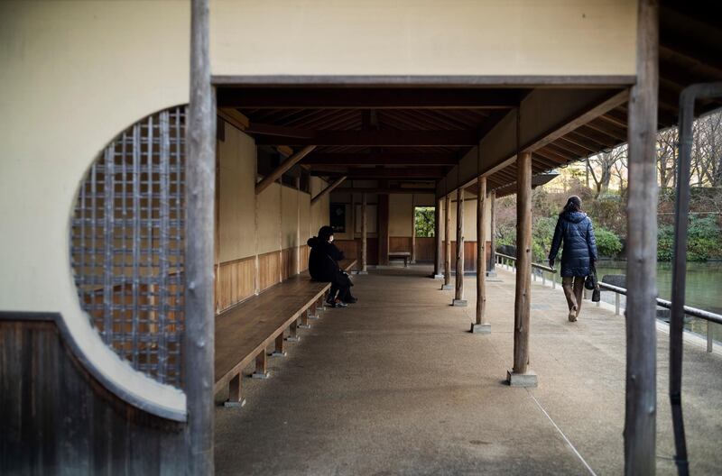 People wearing face masks rest at Hinokicho Park in Tokyo. AP Photo