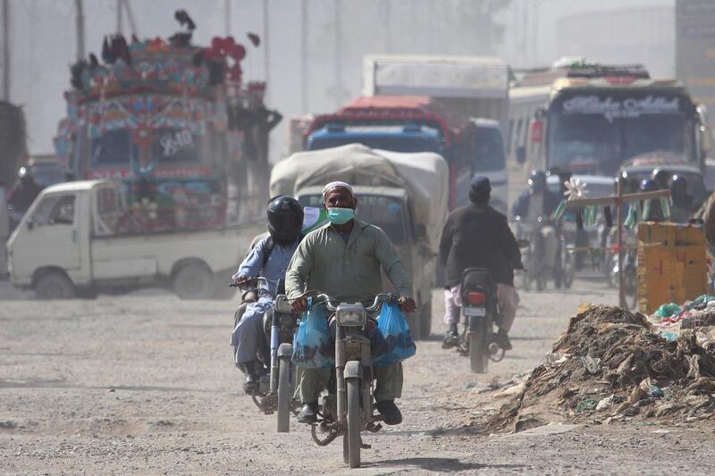 A man wears a face mask as he rides a motorcycle in Karachi, Pakistan. Many countries around the world are battling a surge in coronavirus infections. EPA