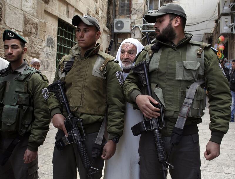 A Palestinian man stands behind Israeli security forces standing guard at an alleyway leading to the Aqsa Mosque compound on February 25, 2014. Ahmad Gharabli / AFP