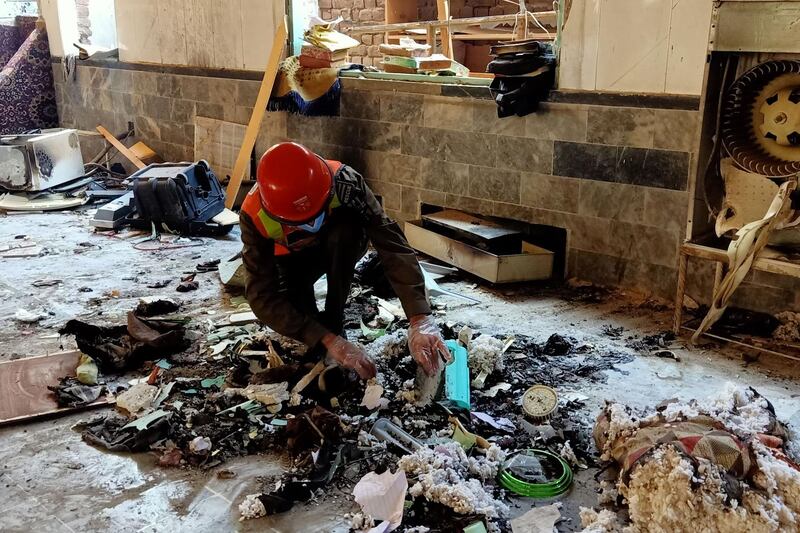A rescue worker examines remains at the site of a blast at a religious school in Peshawar. AFP
