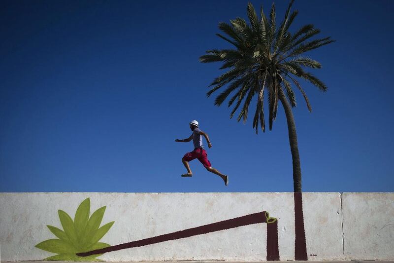 A man runs along a mural by Polish artist M-CITY decorating a wall in the village of Erriadh. Joel Saget / AFP Photo