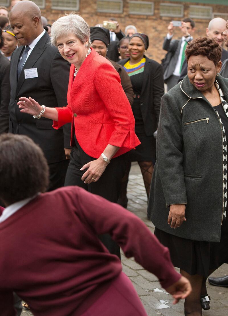 British Prime Minister Theresa dances with children during a visit to the ID Mkhize High School in Gugulethu, Cape Town, South Africa, Tuesday, Aug. 28, 2018. May has started a three-nation visit to Africa and will continue to Nigeria and Kenya. (Rodger Bosch/Pool Photo via AP)