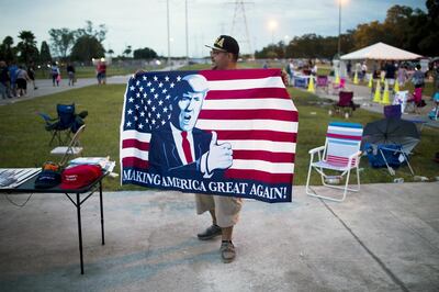 A vendor holds an American flag with the image of U.S. President Donald Trump outside the venue of a rally with Trump in Tampa, Florida, U.S., on Tuesday, July 31, 2018. Iranian Foreign Minister Javad Zarif pushed back on Trump's suggestion that he'd be willing to meet President Hassan Rouhani with "no preconditions," saying the two countries spent plenty of time in negotiations already. Photographer: Zack Wittman/Bloomberg