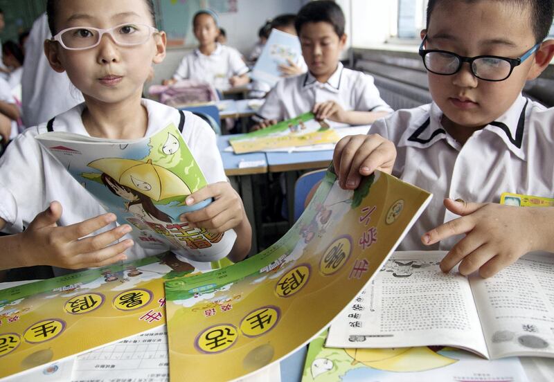 --FILE--Young near-sighted Chinese students wearing glasses receive textbooks in the classroom at a primary school ahead of the summer vacation in Boxing county, Binzhou city, east China's Shandong province, 3 July 2014.

The number of Chinese wearing glasses is rising. Most new adoptees are children. In 1970 fewer than a third of 16- to 18-year-olds were deemed to be short-sighted (meaning that distant objects are blurred). Now nearly four-fifths are, and even more in some urban areas. A fifth of these have "high" myopia, that is, anything beyond 16 centimetres is unclear. The fastest increase is among primary school children, over 40% of whom are short-sighted, double the rate in 2000. That compares with less than 10% of this age group in America or Germany. The incidence of myopia is high across East Asia, afflicting 80-90% of urban 18-year-olds in Singapore, South Korea and Taiwan. The problem is social rather than genetic. A 2012 study of 15,000 children in the Beijing area found that poor sight was significantly associated with more time spent studying, reading or using electronic devices, along with less time spent outdoors. The biggest factor in short-sightedness is a lack of time spent outdoors. Exposure to daylight helps the retina to release a chemical that slows down an increase in the eye's axial length, which is what most often causes myopia. Schoolchildren in China are often made to take a nap after lunch rather than play outside; they then go home to do far more homework than anywhere outside East Asia. The older children in China are, the more they stay indoors, and not because of the country's notorious pollution.