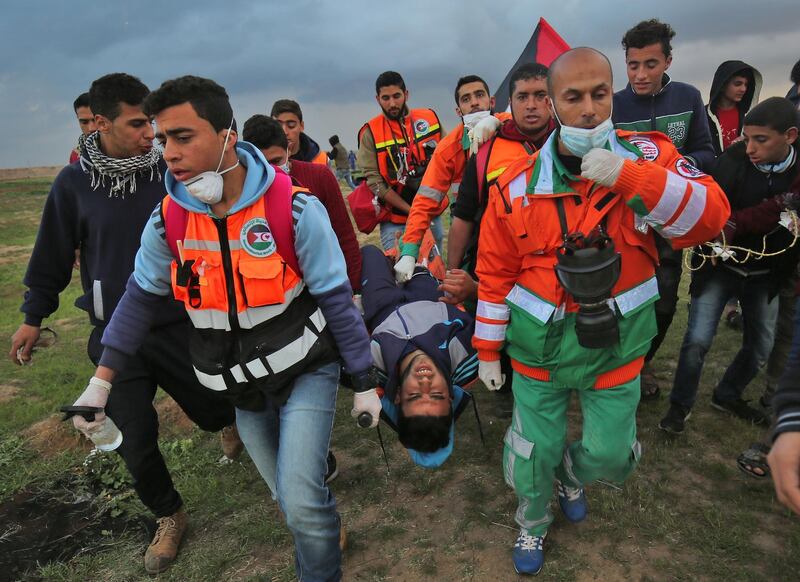 Palestinian paramedics carry a youth injured during clashes following a demonstration along the border with Israel east of Gaza City.  AFP