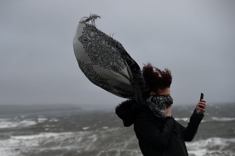 A woman takes a picture during storm Ophelia in the County Clare town of Lahinch, Ireland. Clodagh Kilcoyne / Reuters
