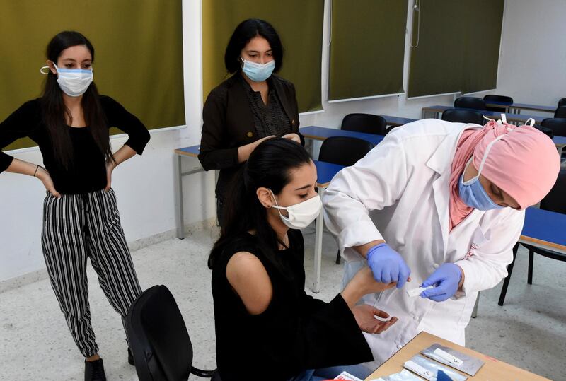 An employee of the Tunisian Health ministry takes a blood sample to test a student for Covid-19 in a school of Tunis. AP Photo