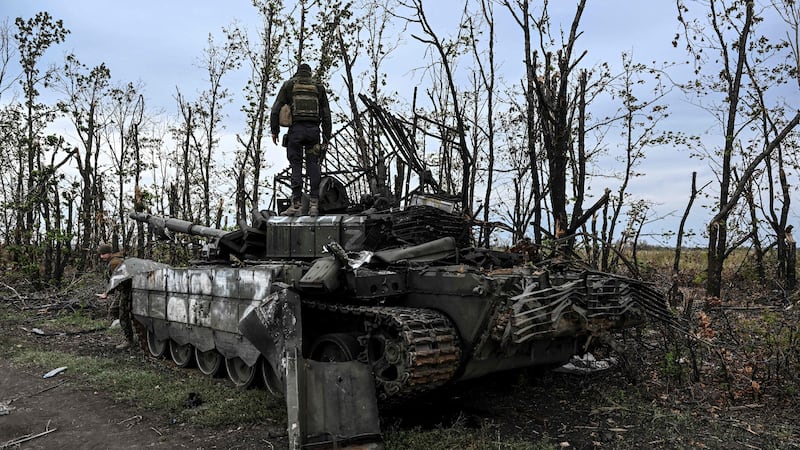 A Ukrainian soldier assesses an abandoned Russian tank near a village in Kharkiv, eastern Ukraine. AFP