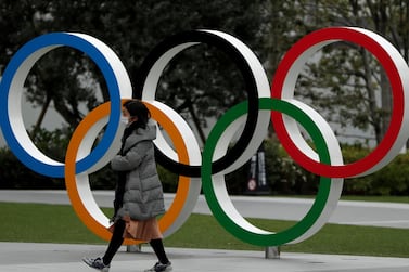 A woman wearing a protective face mask walks past the Olympic rings in front of the Japan Olympics Museum, in Tokyo. Reuters