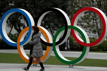 A woman wearing a protective face mask walks past the Olympic rings in front of the Japan Olympics Museum, in Tokyo. Reuters