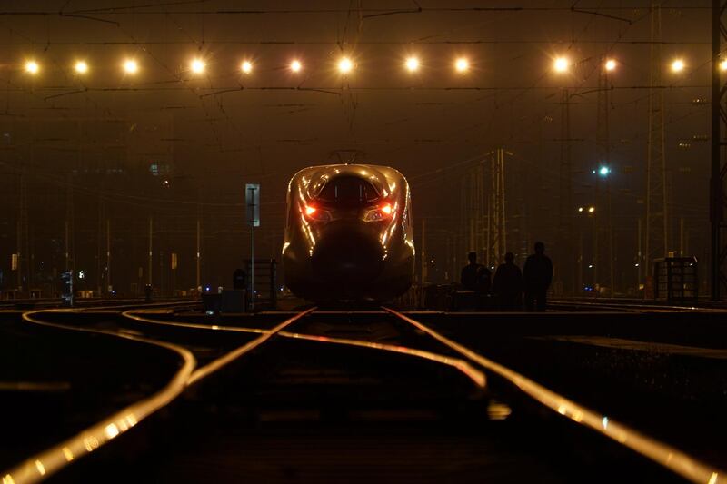 Workers walk next to a bullet train in Guangzhou, Guangdong province, China. Reuters