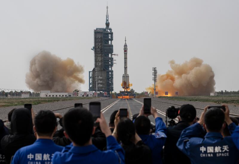 Members of the China Manned Space Agency and visitors watch as the Long March 2F rocket launches. Getty