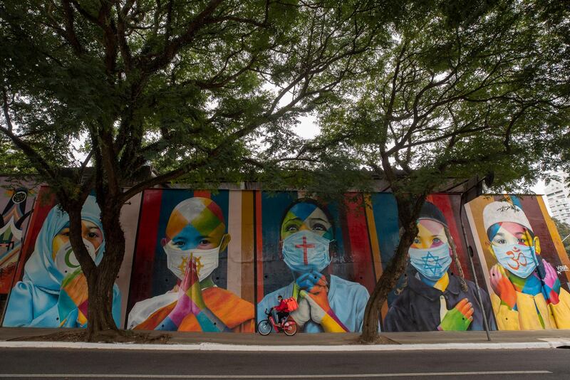 A cyclist rides past a mural created by Brazilian street artist Eduardo Kobra that features children wearing masks with religious symbols from Islam, Buddhism, Christianity, Judaism and Hinduism, amid the Covid-19 pandemic in Sao Paulo, Brazil. AP Photo
