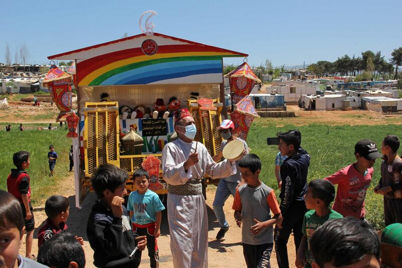 Children gather around a man beating a drum at a Syrian refugee camp in the southern Lebanese town of Ebel Al Saqi during Ramadan. AFP