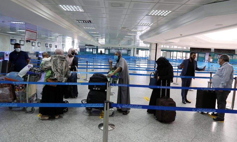 Passengers wearing face masks wait in line for check-in for their repatriation flight for Libya, at the Tunis Carthage International Airport in Tunis, Tunisia.  EPA