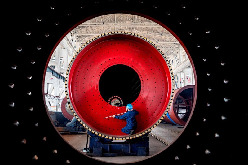 An employee measures a newly manufactured ball mill machine at a factory in Nantong, Jiangsu province, China.  Reuters