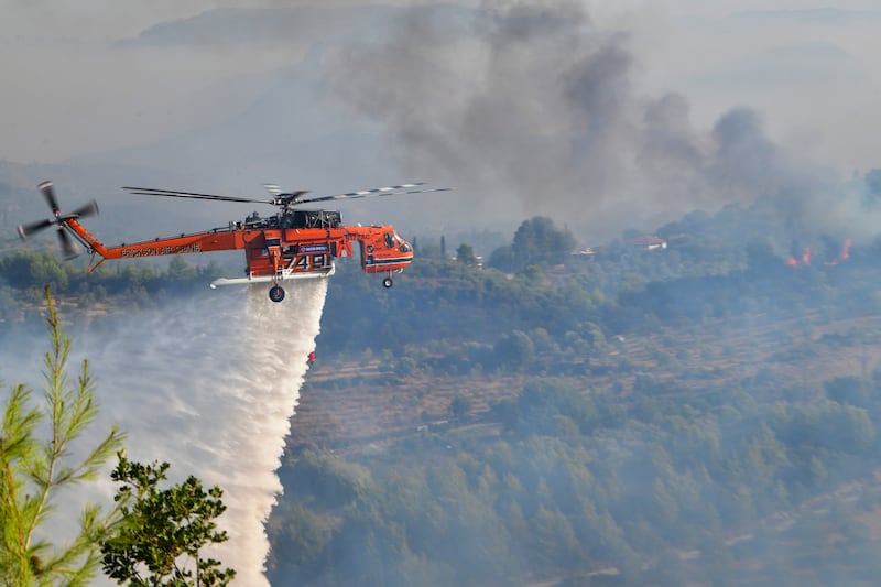 A helicopter drops water on a bush fire in Olympia, western Greece on Thursday.