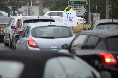 BRIGHTON, ENGLAND - SEPTEMBER 25: A man holds a sign directing the heavy traffic queues outside a busy petrol station in Brighton, England. Getty 